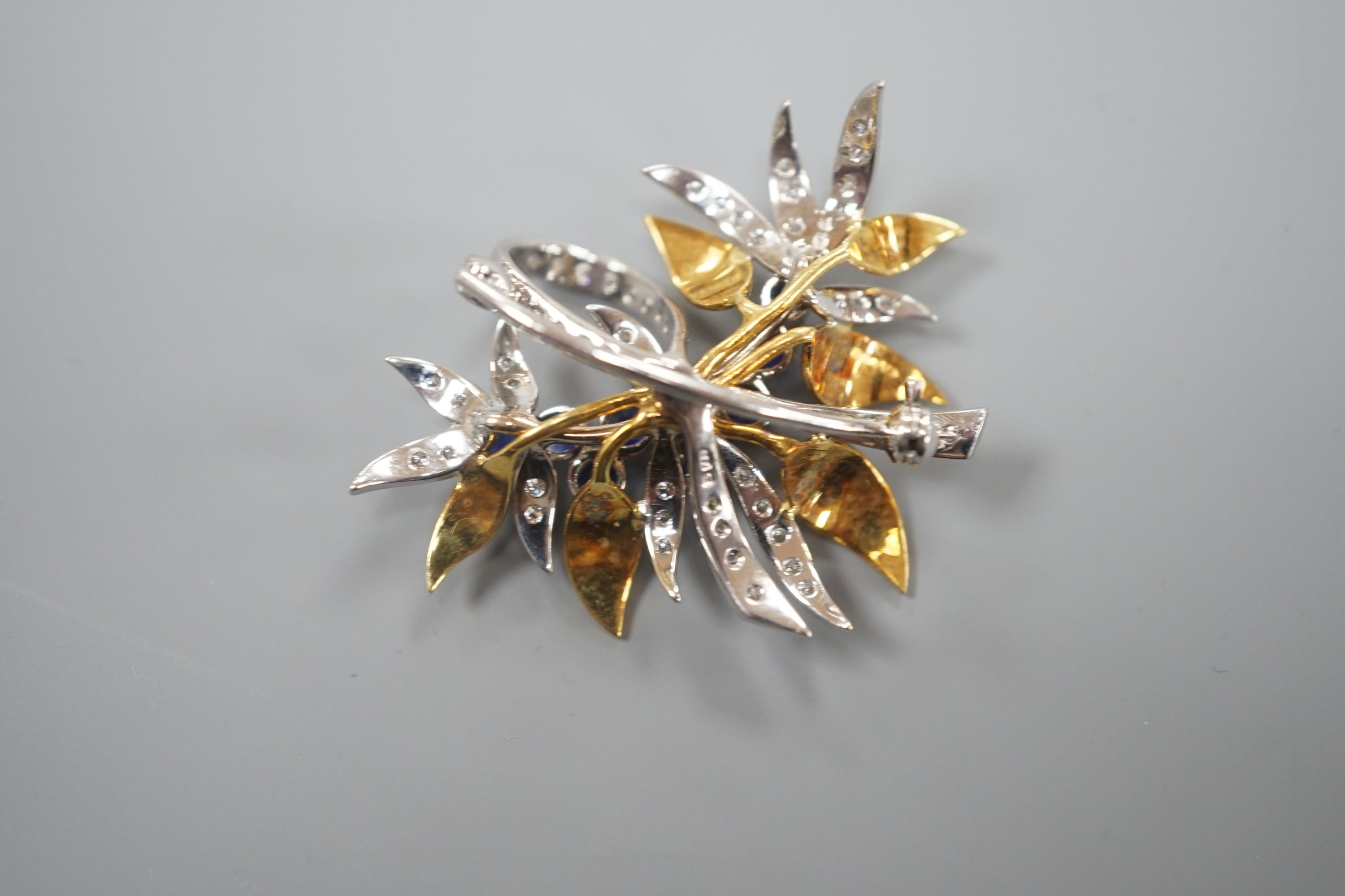 A modern 18ct two colour gold, sapphire and diamond set floral spray brooch, by Cropp & Farr, 38mm, gross weight 11.9 grams.